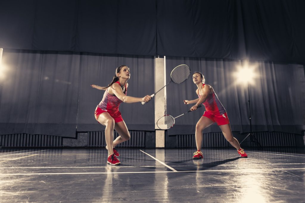Young women playing badminton at gym