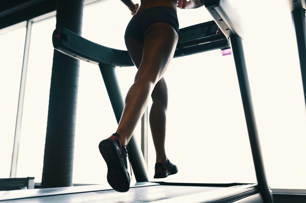 Early morning sport, female legs running on the gym treadmill early morning